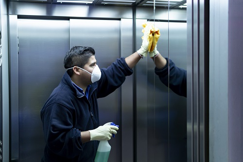 Man Wearing a Mask and Cleaning Elevator Man Wearing a Mask and Cleaning Elevator