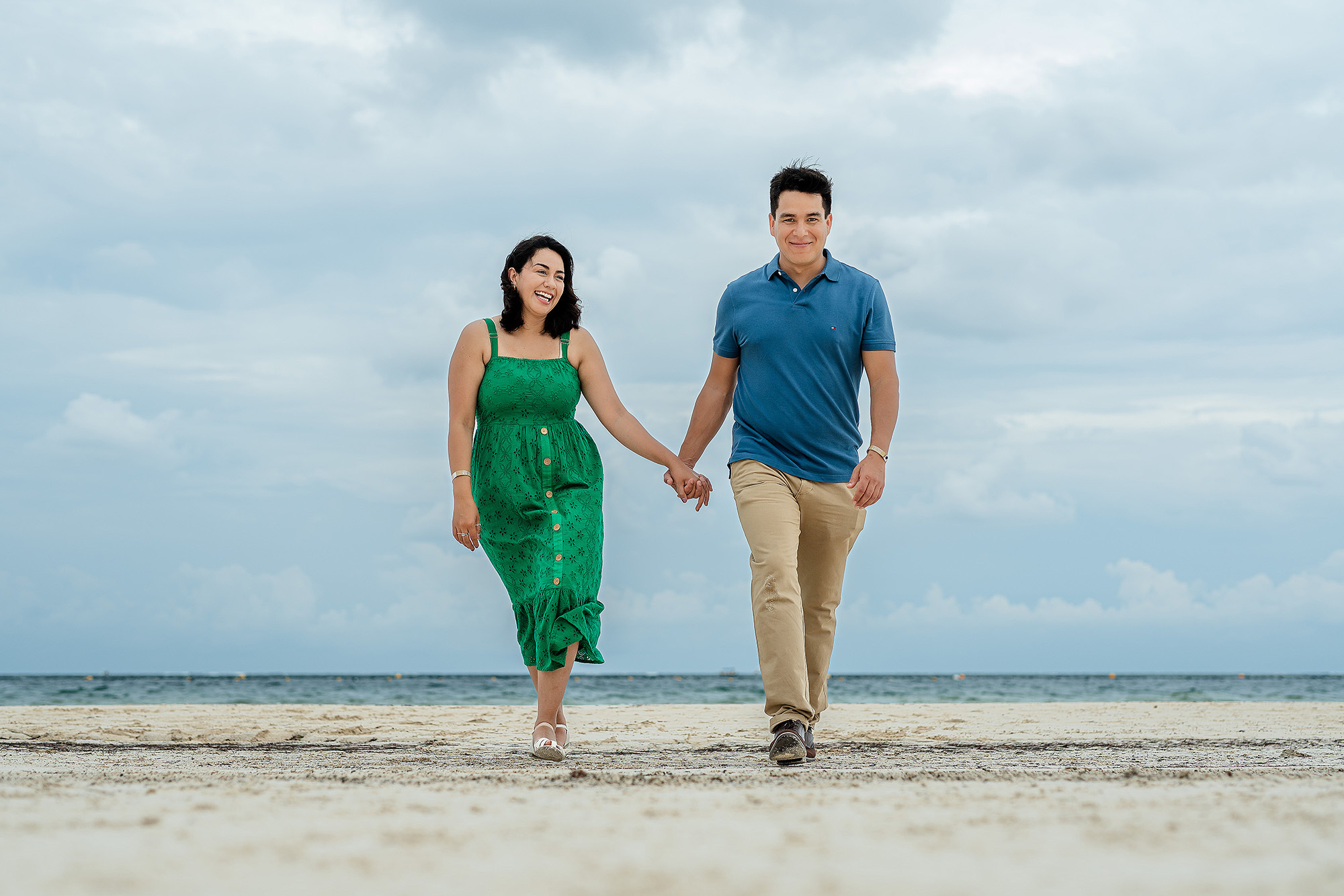 Couple walking by the ocean during an engagement session in the Riviera Maya, Mexico.