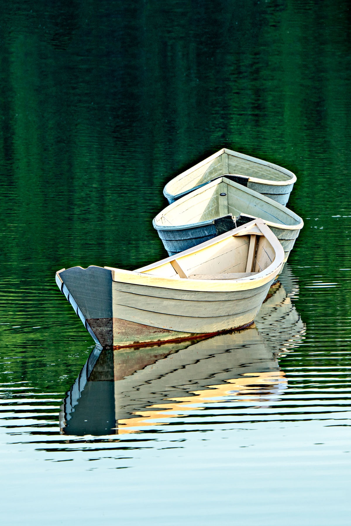 THREE DORIES - These three boats(dories) are anchored in the water in the town of Kennebunkport, Maine. Wind, tide and activity cause them to move constantly. They appear to dance in the water. Light and water level change the show throughout the day. They have become a town icon. This is one of many photos I took while there.