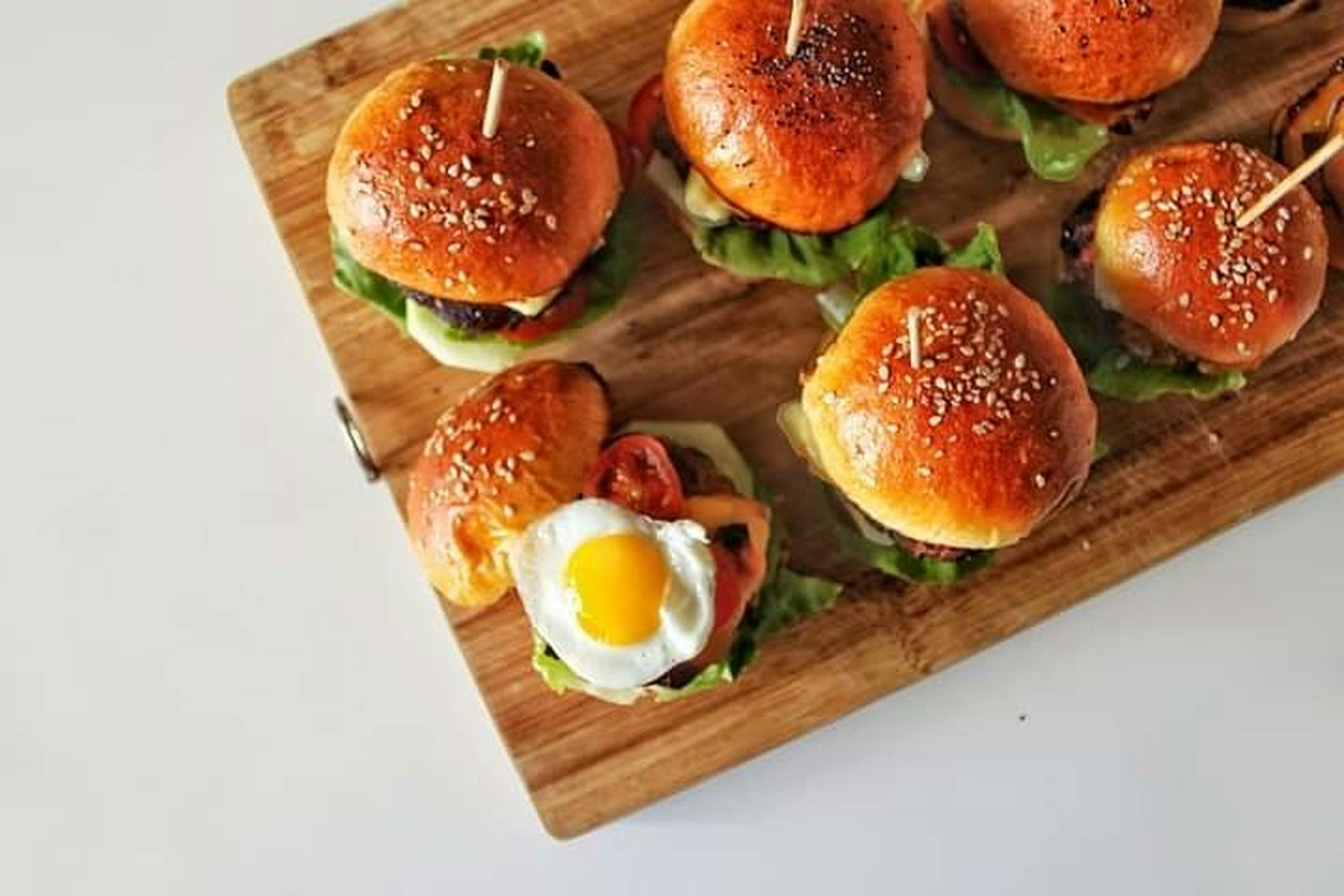 tomate en rodajas y vegetales verdes en una tabla de cortar blanca