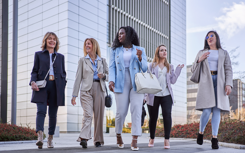 Several women walking outside of tall buildings Several women walking outside of tall buildings