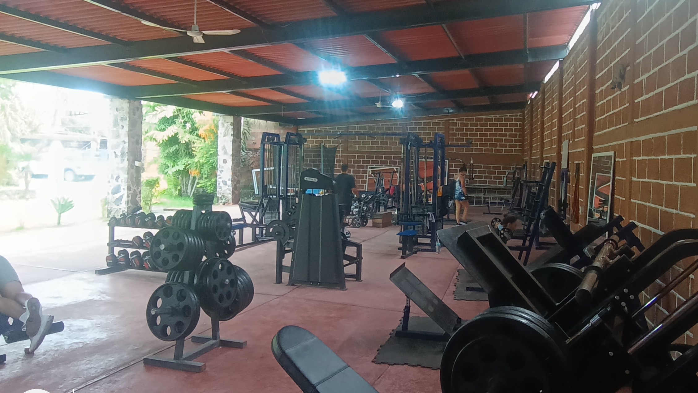 Pareja entrenando en un gimnasio, ambos de pie frente a frente sonriendo, con atuendos deportivos y largas colas de caballo.