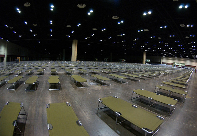 A large building with many empty cots lined up A large building with many empty cots lined up
