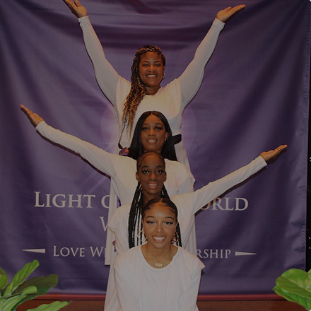 Four women smiling with their arms up