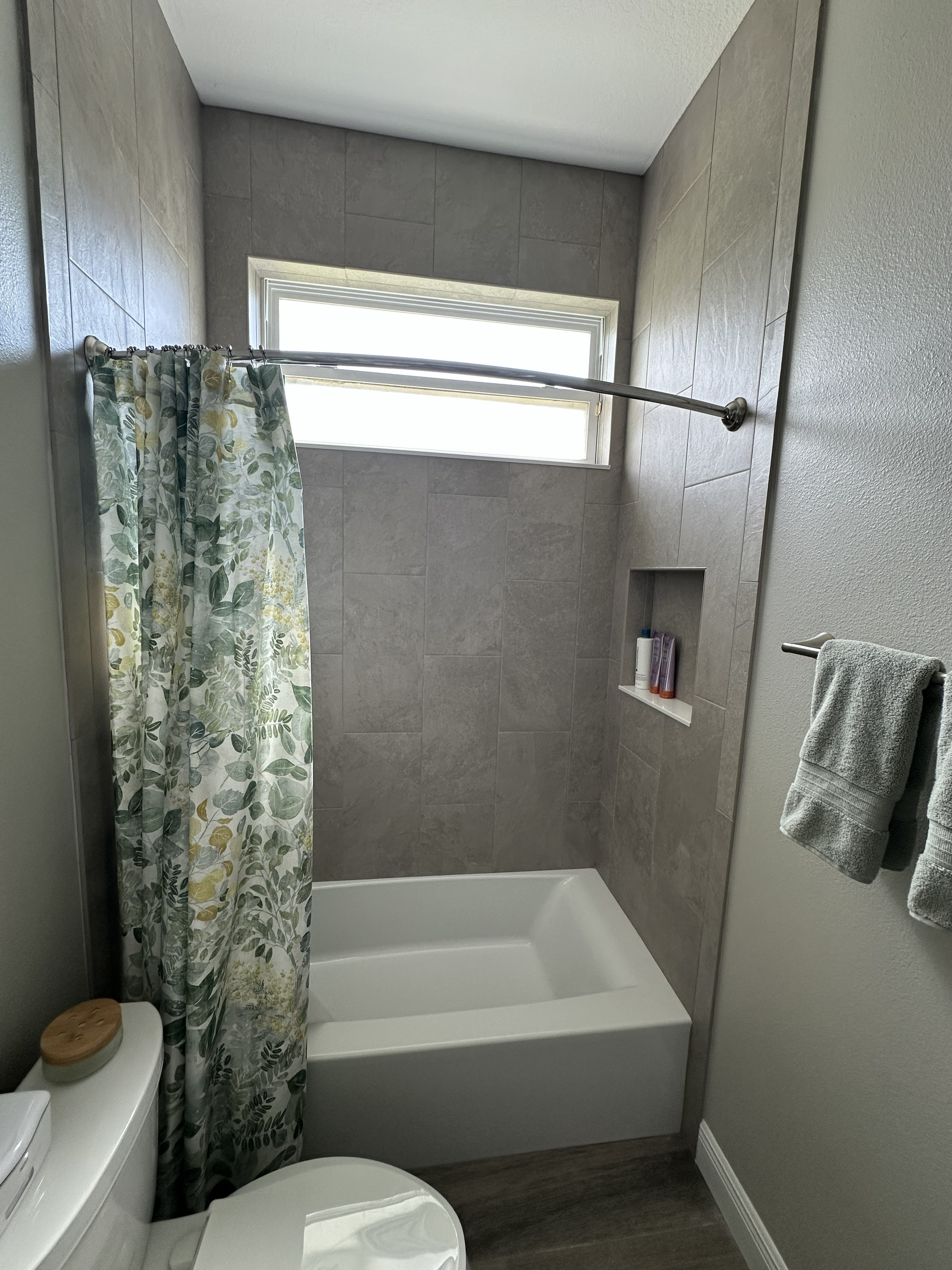 Classic tub-shower combo with 12x24 gray wall tile extending to the ceiling and a built-in niche for added storage.