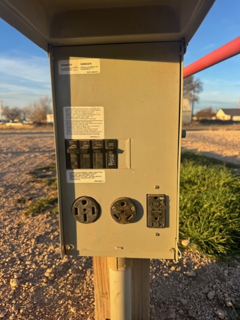 Scenic RV park with multiple motorhomes and campers surrounded by lush trees and green grass under a blue sky with white clouds.