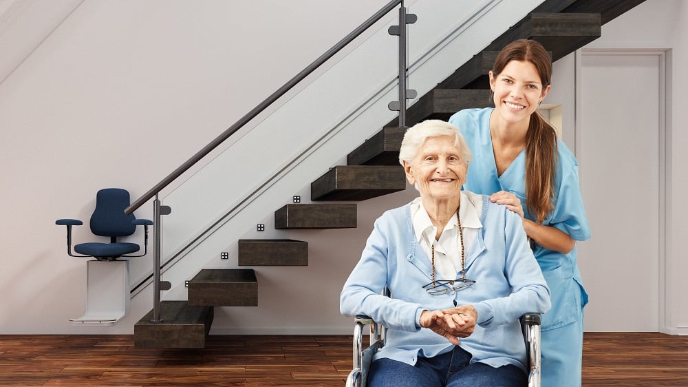 Woman in wheelchair and caretaker in front of stairlift