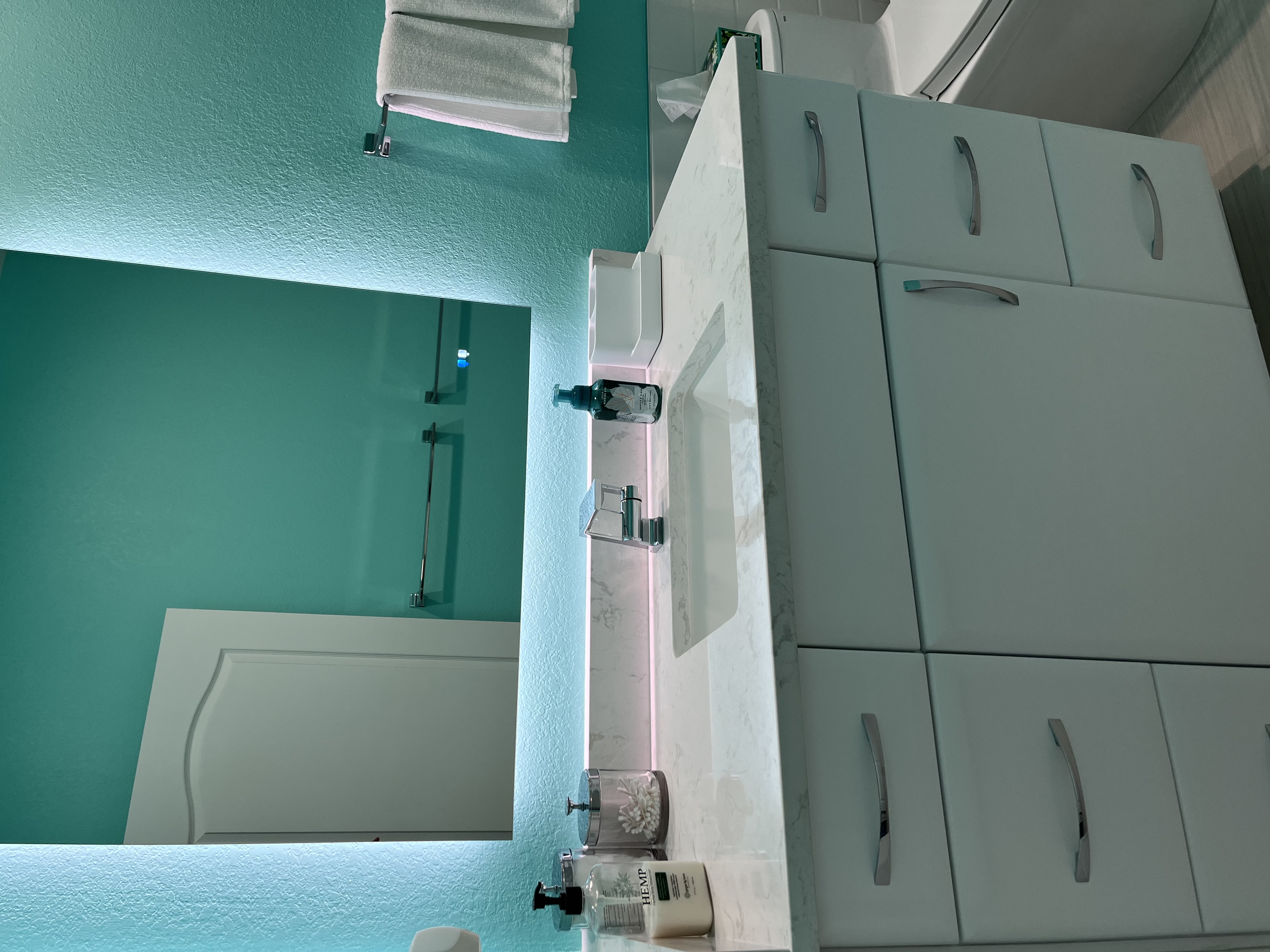 Fresh white vanity with Cambria quartz and matching backsplash with a perfectly placed backlit mirror.