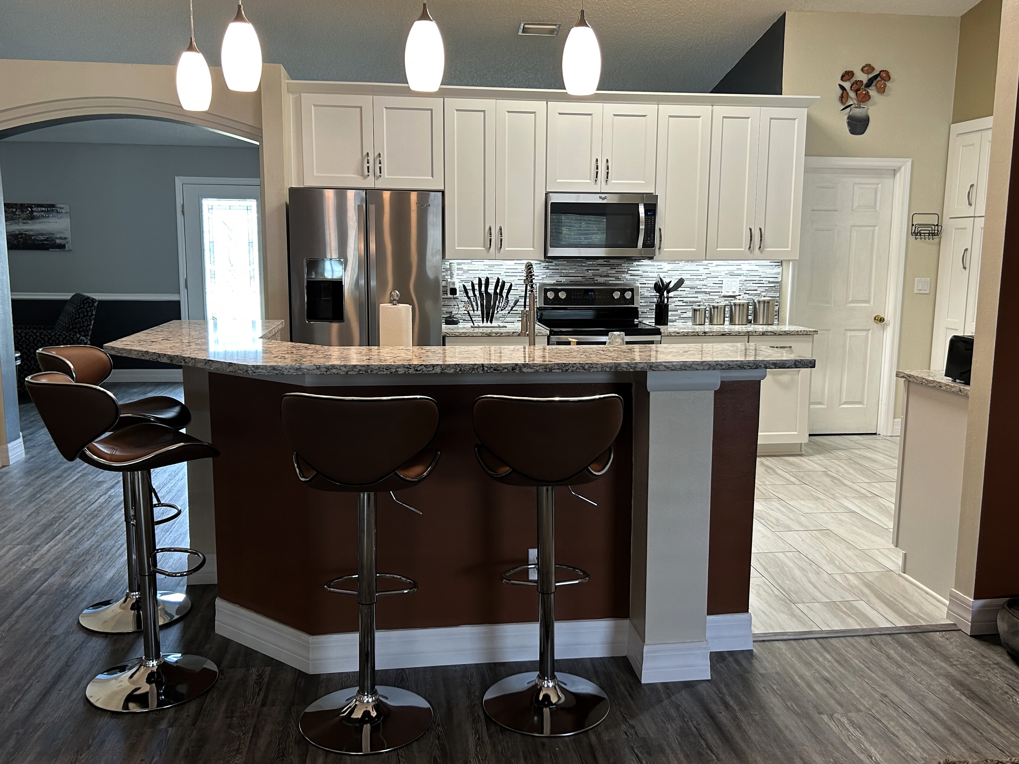 Beautiful kitchen featuring maple semi-custom wood cabinetry painted white with satin nickel handles.  The upper Cambria quartz bar overhang allows for seating and entertaining.