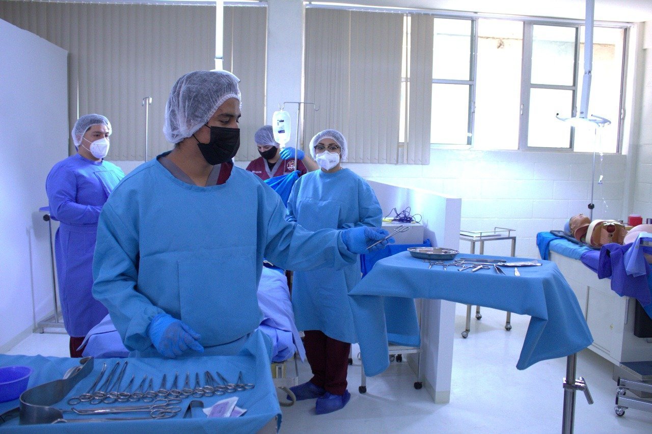 Equipo médico en una sala de cirugía con instrumentos quirúrgicos y profesionales de la salud en batas y mascarillas.
