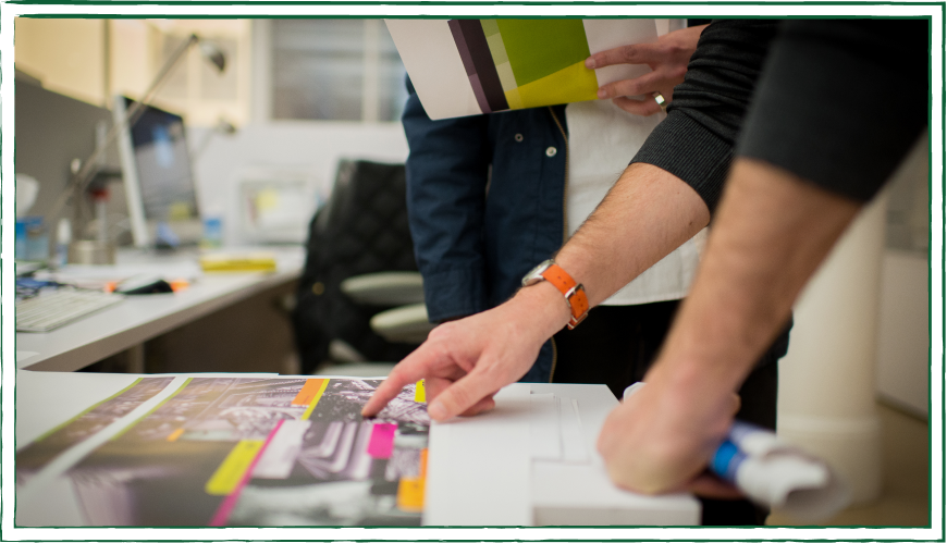 A team looking at projects on a desk A team looking at projects on a desk
