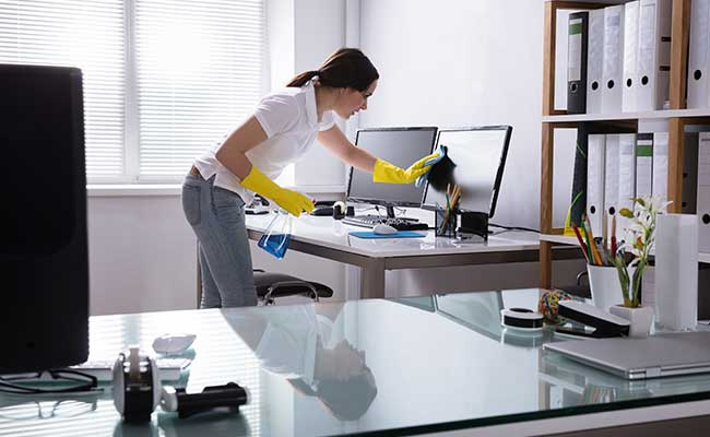 Woman Cleaning Computer In Office