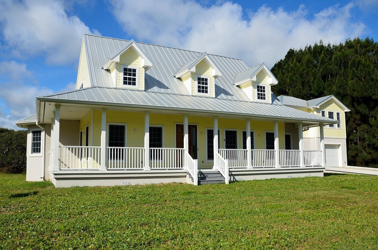 Two story yellow home with a silver metal roof
