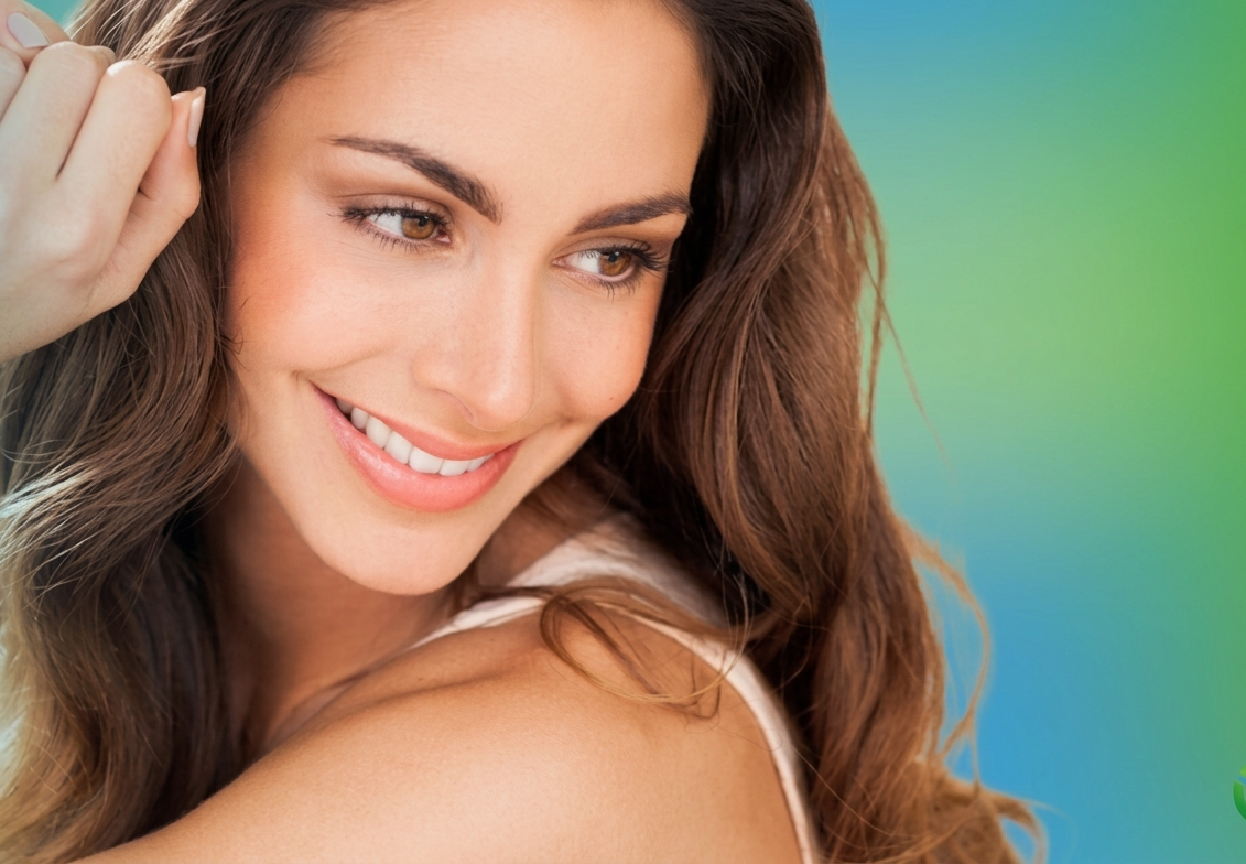 Modern reception area with sleek white counter, two people at computers, indoor plants, and decorative shelving in an office setting.