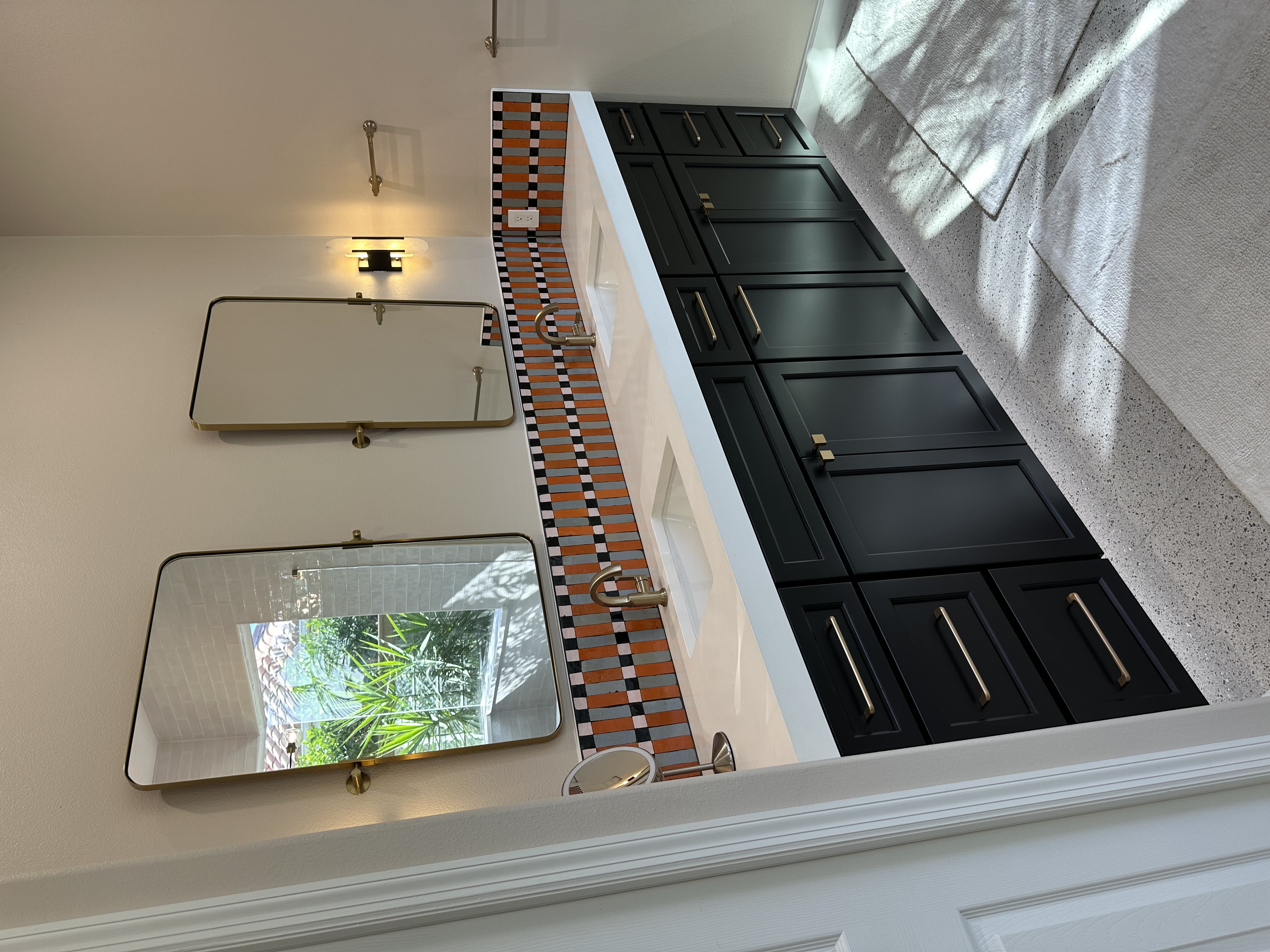 A striking semi-custom vanity painted Carriage Black with quartz countertops,
and a playful, unique tiled backsplash that adds personality and charm.