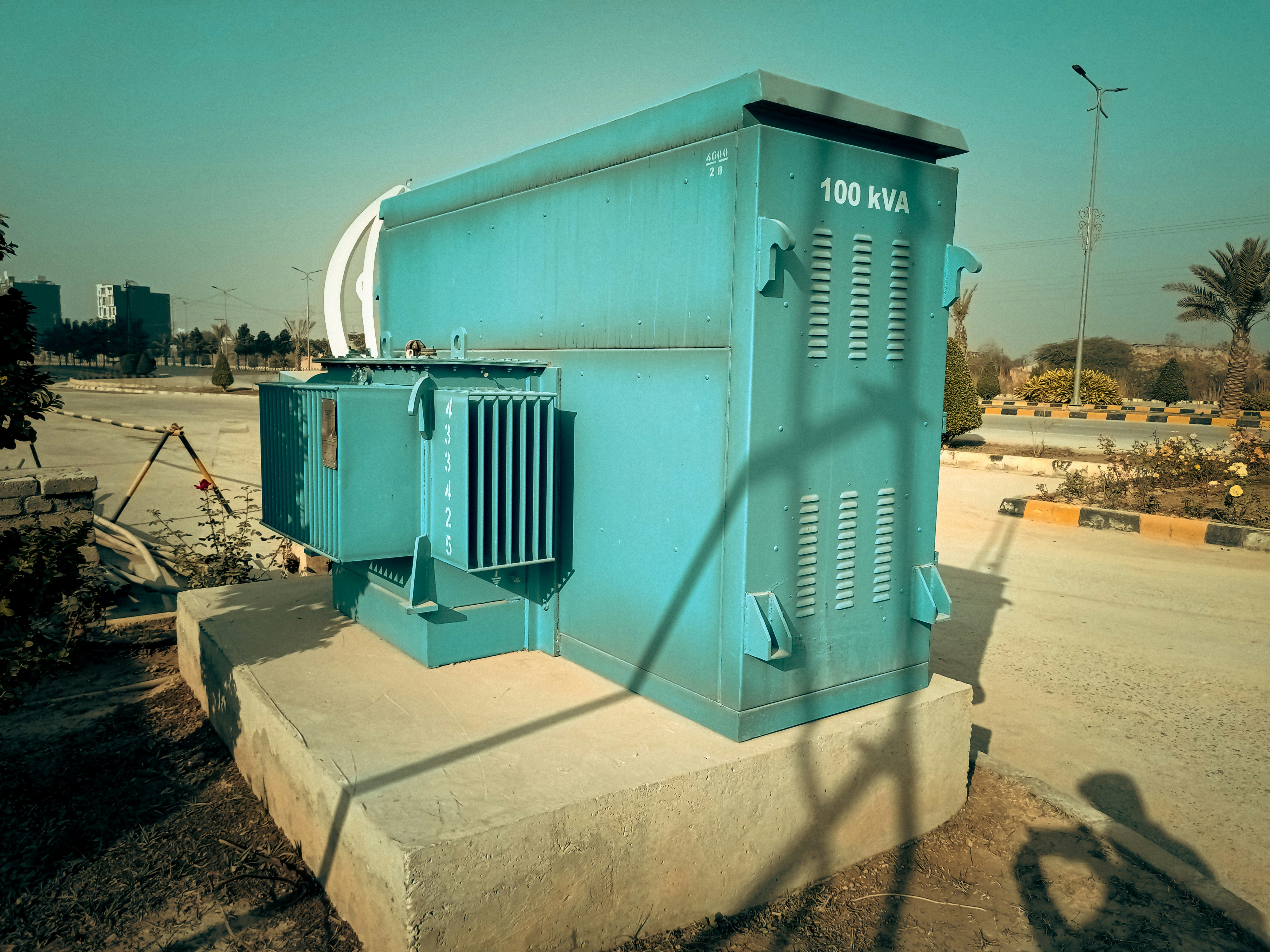 Transformador eléctrico industrial azul de 100 kVA instalado sobre plataforma de concreto en zona urbana