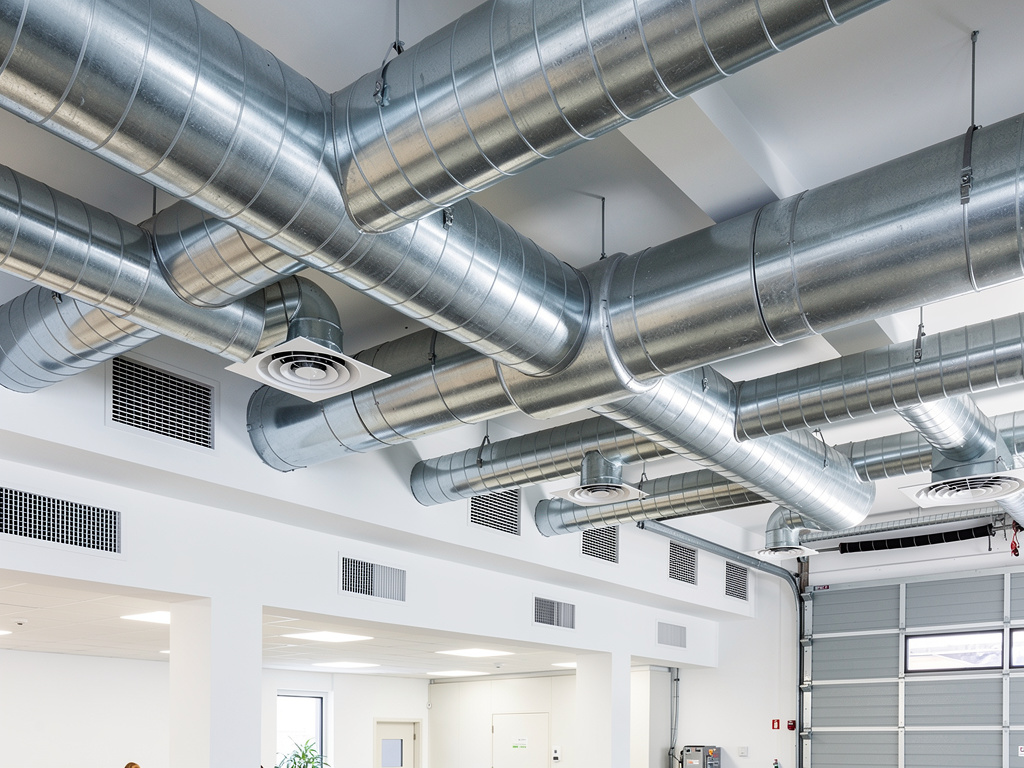 Conductos metálicos de ventilación y sistema HVAC industrial instalados en el techo de un edificio