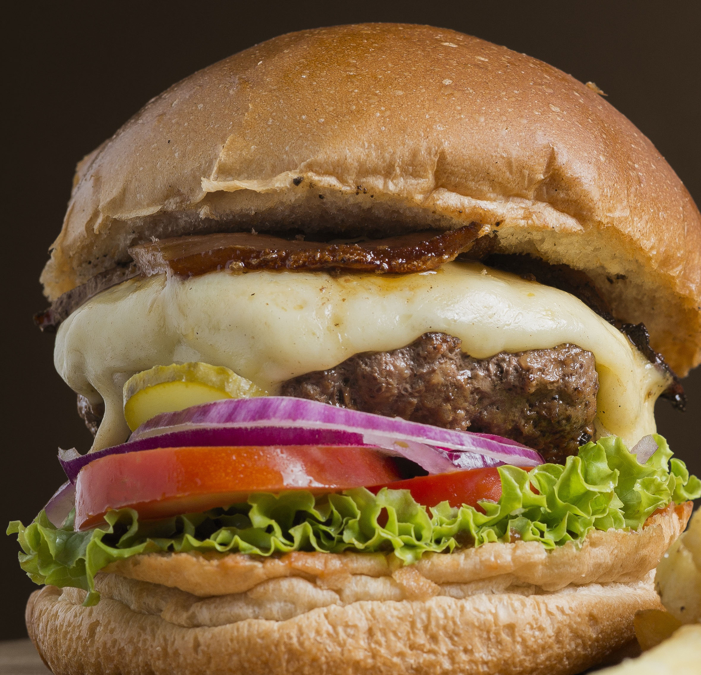 Rica Hamburguesa con Carne de Res, Bacon, tomate, lechuga, cebolla, american Cheese, Aderezada con catchup, salsa cheedar y mayonesa.