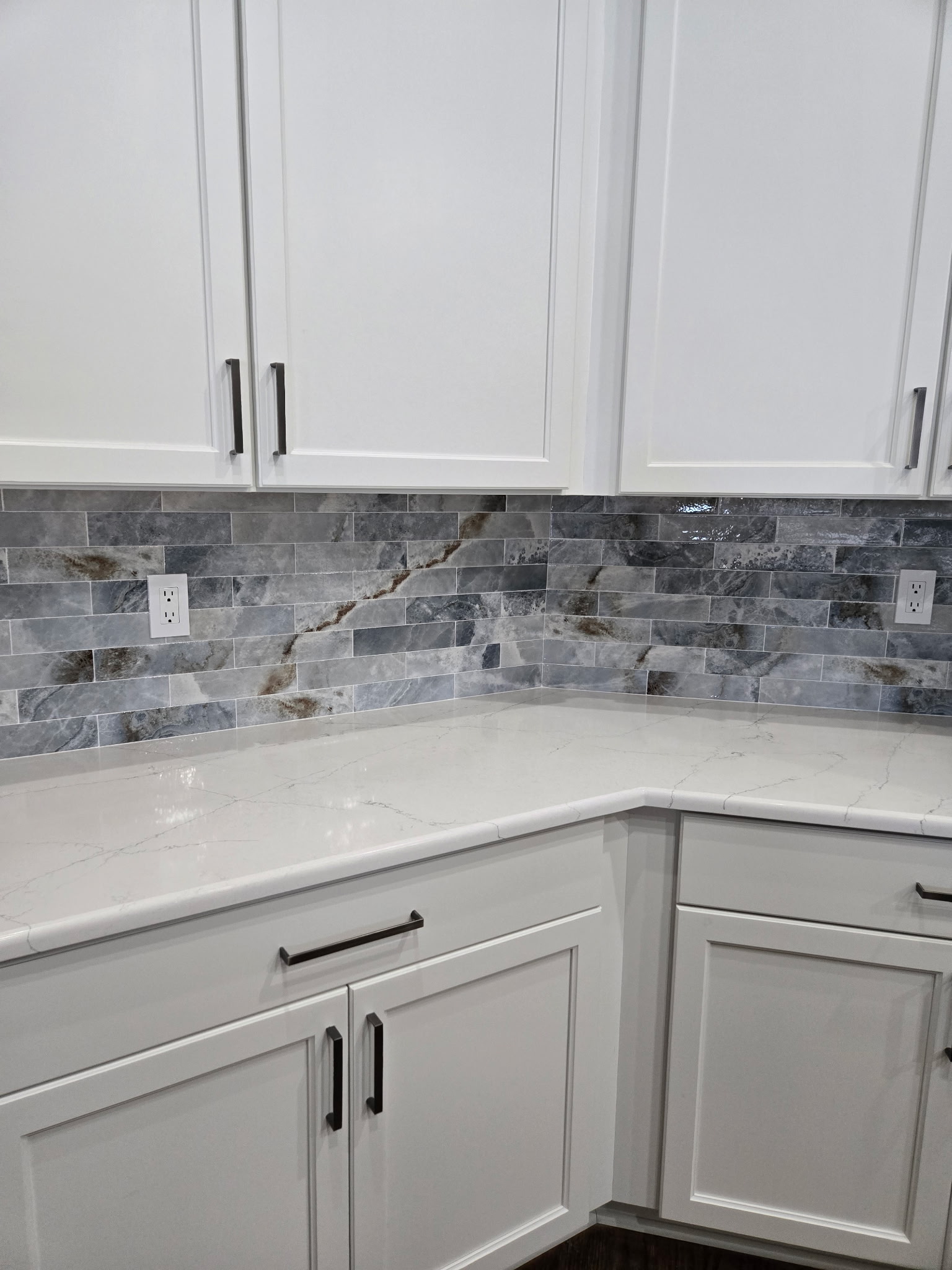 The bright quartz countertop beautifully highlights the backsplash, creating a stunning contrast that elevates the entire kitchen.