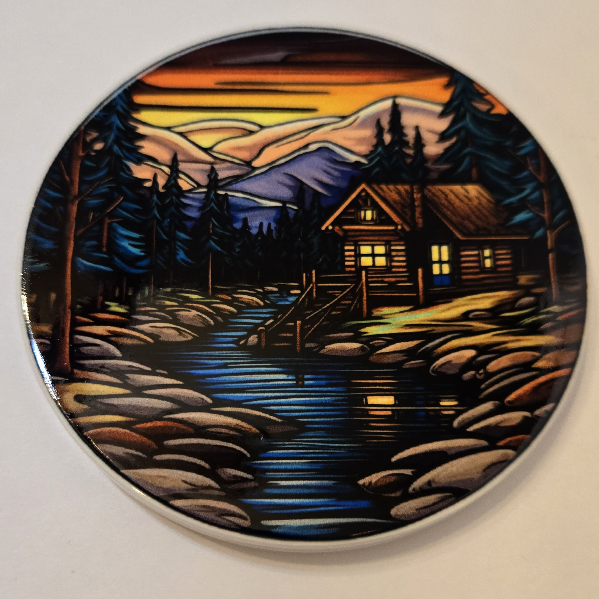 Round ceramic coaster with a stained glass cabin design