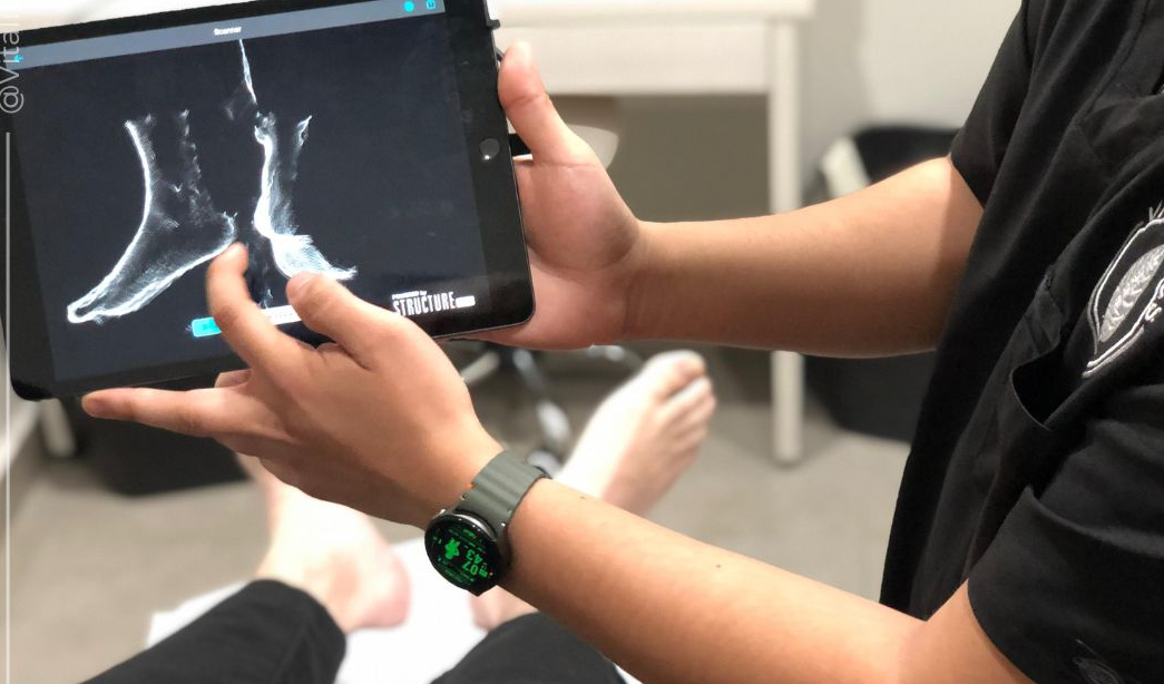 Médico en cirugía vistiendo bata, mascarilla y guantes en una sala de operaciones moderna con equipos médicos.