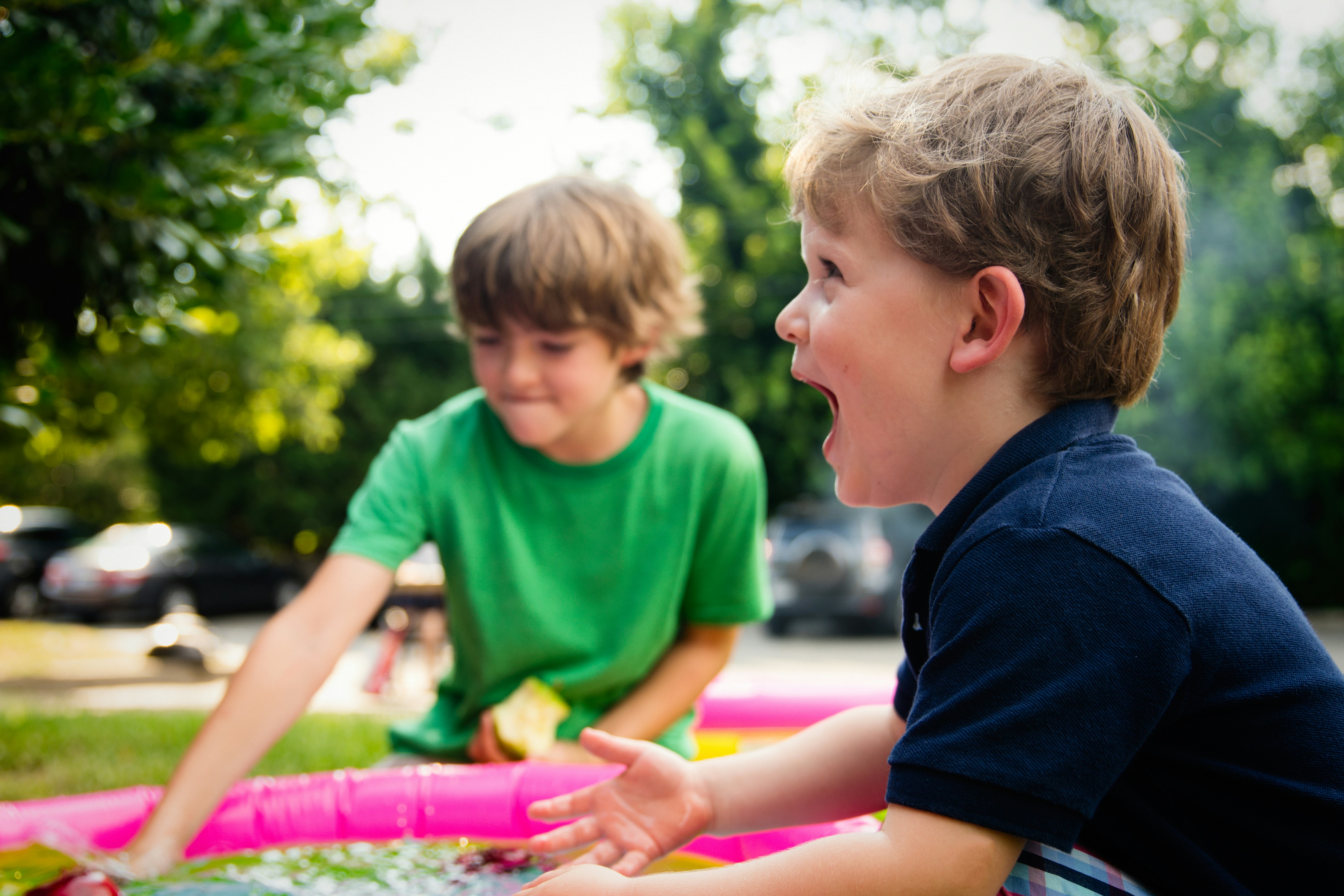 Niños jugando al aire libre en una piscina infantil inflable en un jardín soleado