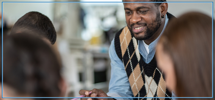 A male African American teacher smiling and looking at students