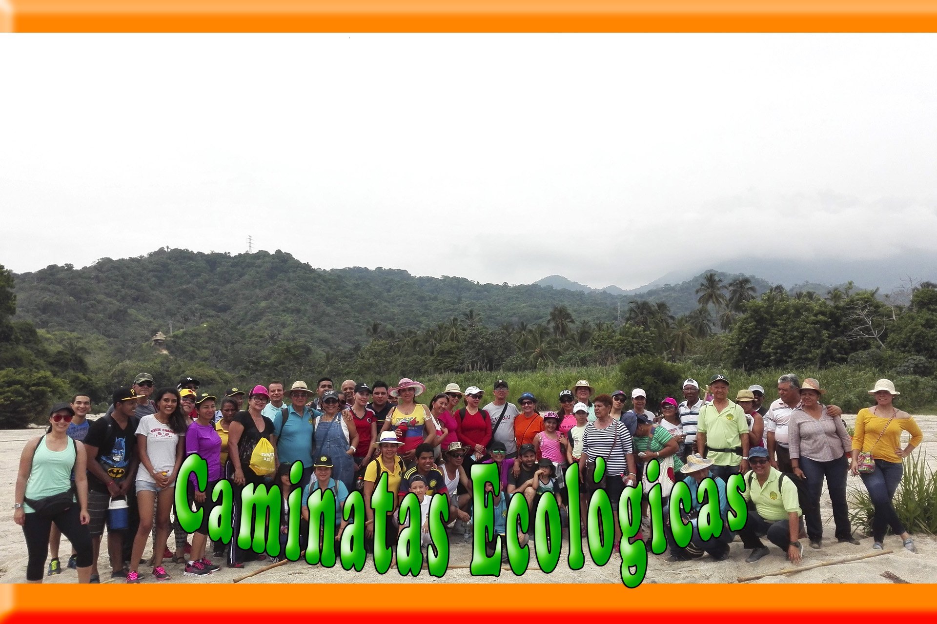 Grupo de personas en una caminata ecológica frente a un paisaje montañoso tropical.