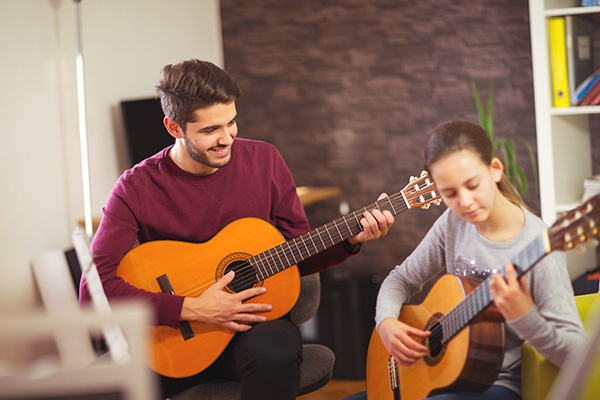 Guitar teacher teaching the little girl