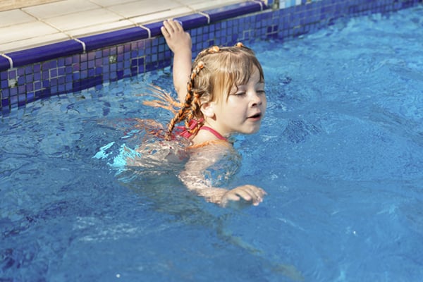 Little Girl Swims in a Swimming Pool