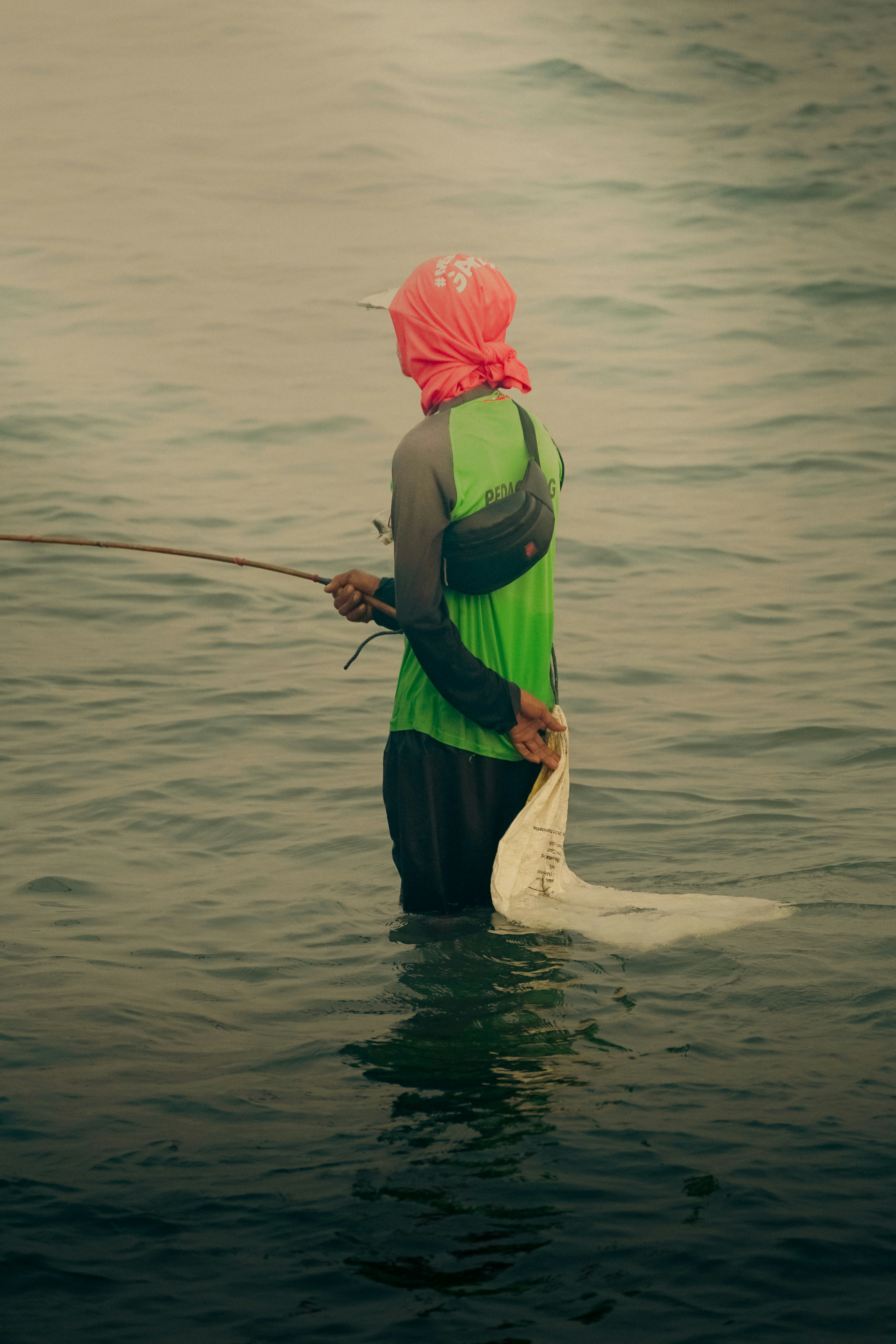 A person in a body of water with a fishing pole