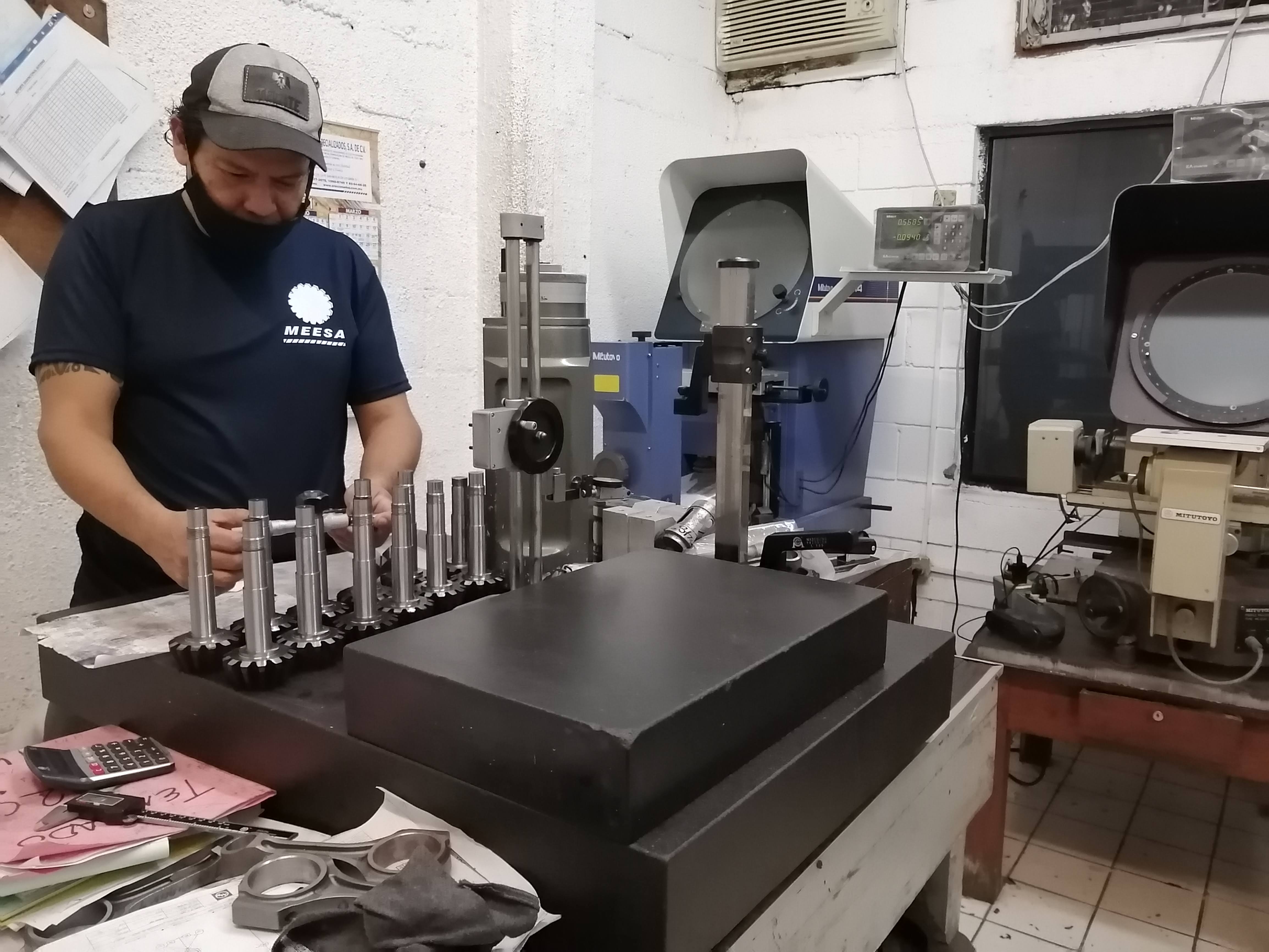 Hombre trabajando en una sala de máquinas industriales con herramientas y equipos de medición.