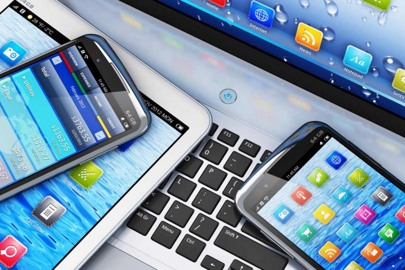 Person holding an iPhone in front of a MacBook