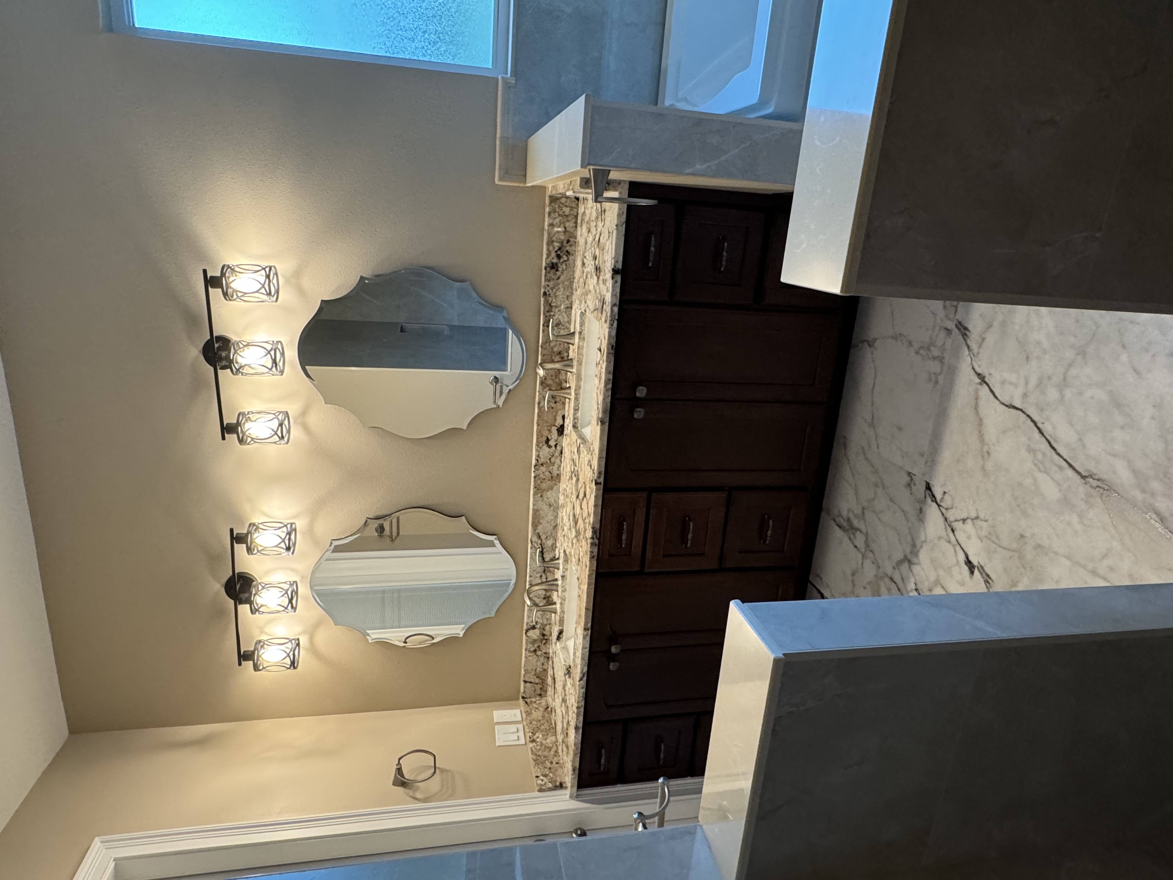 Spacious vanity for two featuring dual sinks, semi-custom maple wood stained Giner Snap cabinetry, and a granite countertop with 4" matching backsplash.