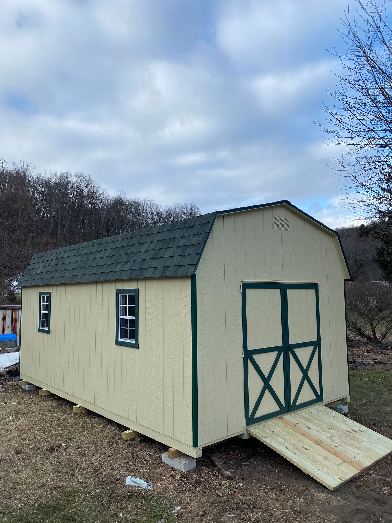 12 x 20 Dutch Colonial In Wood
                                                              
Featuring beige colored wood siding, green colored trim, and green colored 30 year architectural shingles (with tarpaper underlayment), gable vents, 6’ wide double doors, 2- 18”x27” slider windows with screens, pressure treated floor joists.

Featured options: 6x4 treated ramp, perpendicular leveling runners.