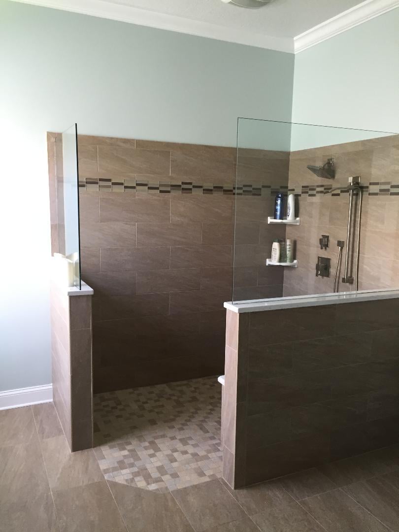 Walk in shower featuring two half glass panels with decorative band of tile.
