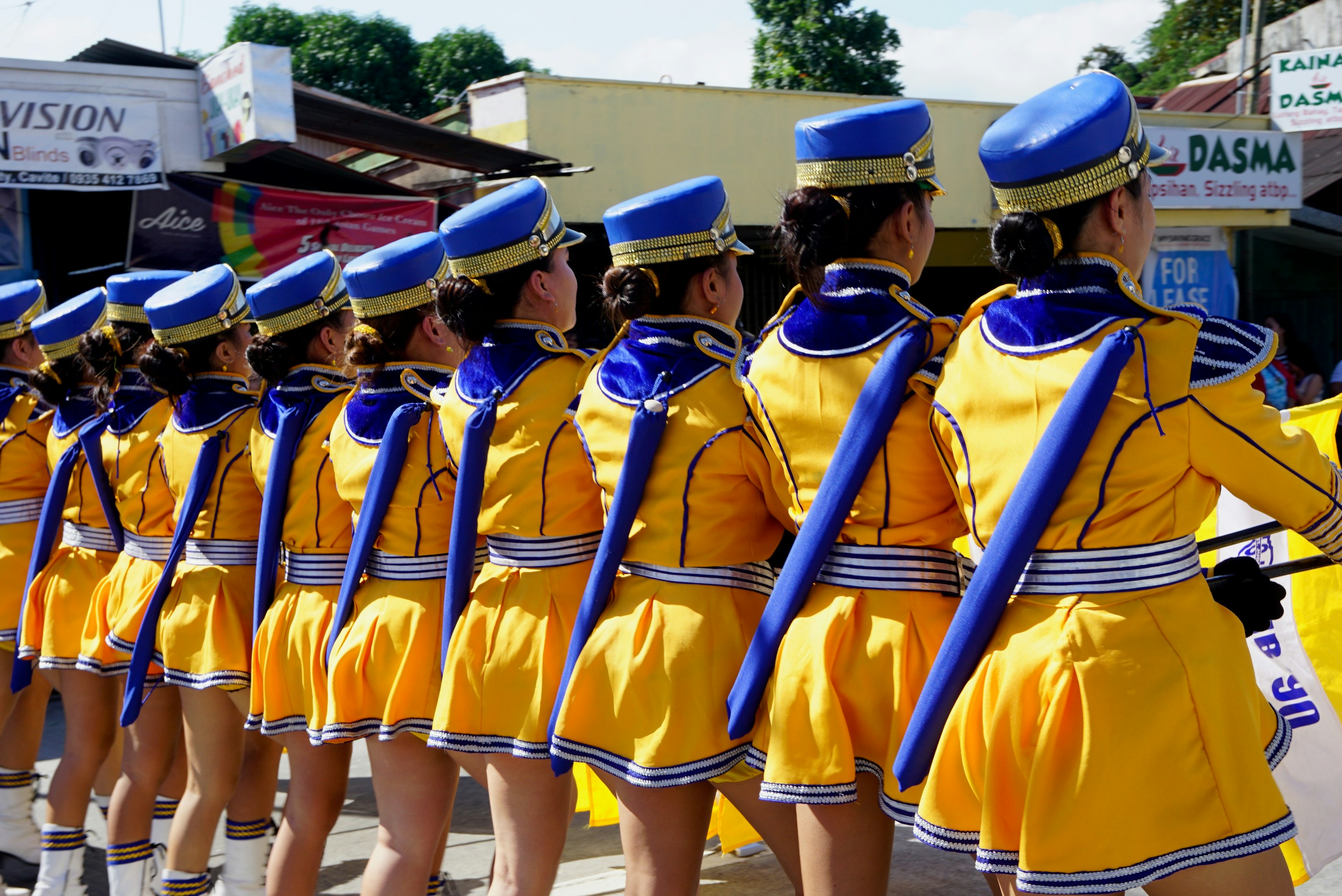 3 mujeres con uniforme amarillo y azul de pie sobre el suelo de concreto gris durante el día