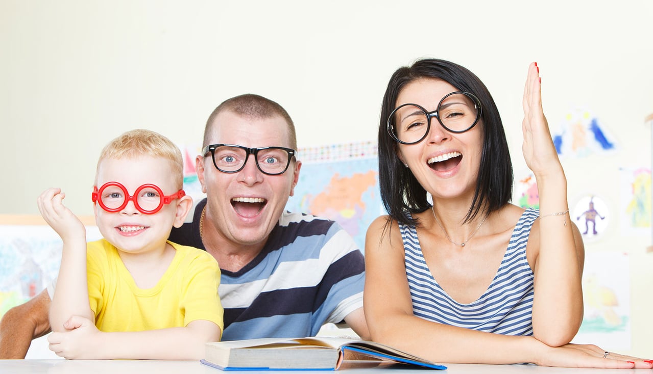 Familia feliz con gafas grandes, niño rubio con camiseta amarilla, hombre de camiseta a rayas y mujer con camiseta a rayas sonriente.