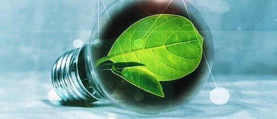 Bombilla con hoja verde en su interior, simbolizando energía sostenible.