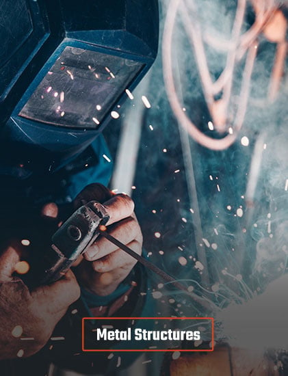 Welder wearing protective helmet working with metal structures, sparks flying in workshop.