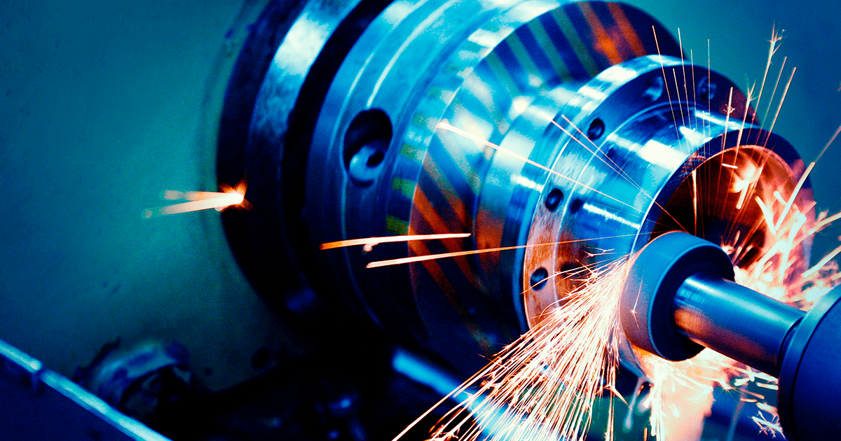 Máquina industrial en funcionamiento con chispas volando durante el proceso de mecanizado en metal.
