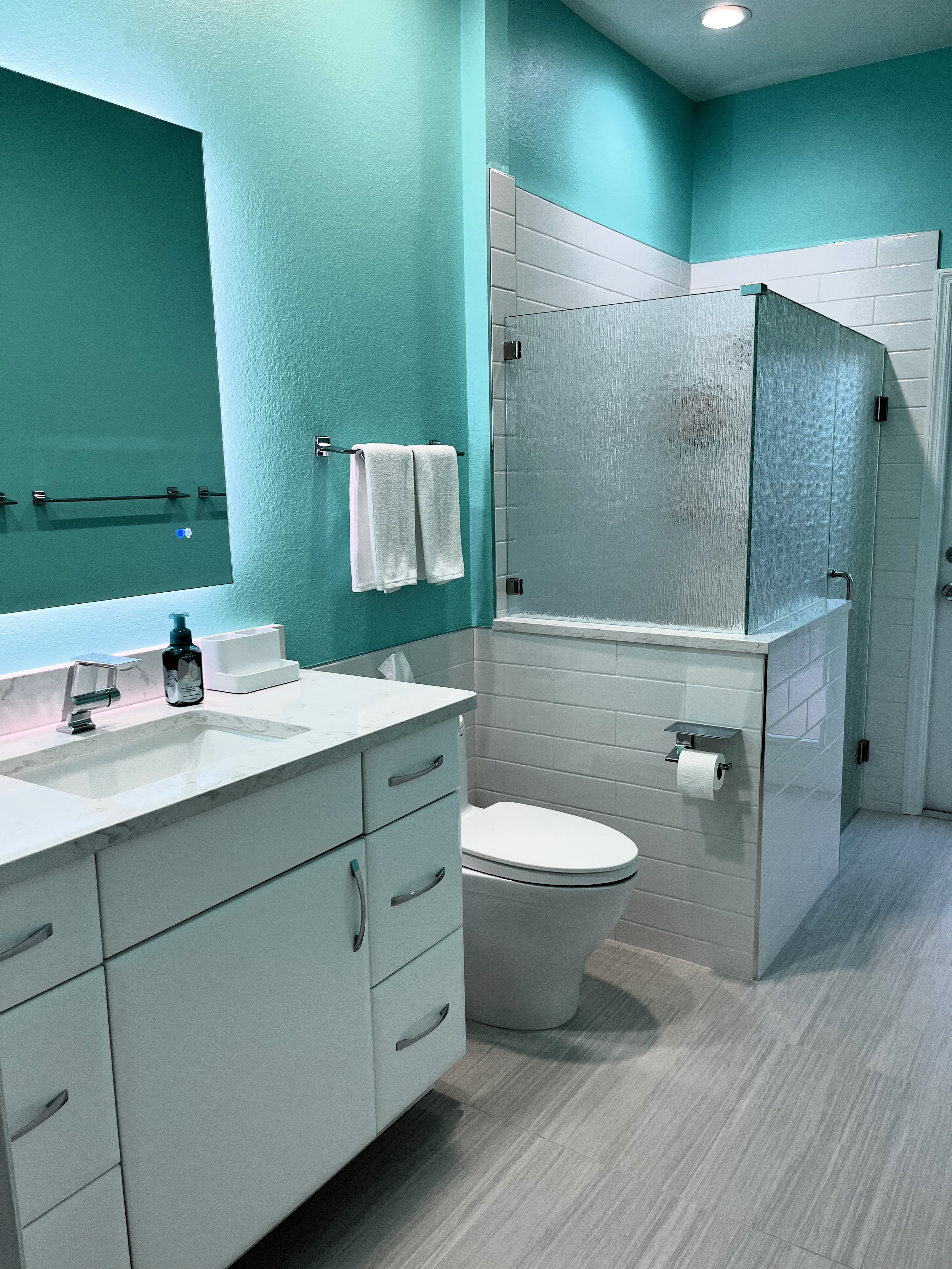 Large bathroom, beautifully tiled, with a walk-in shower showcasing heavy rain glass panels and door. 