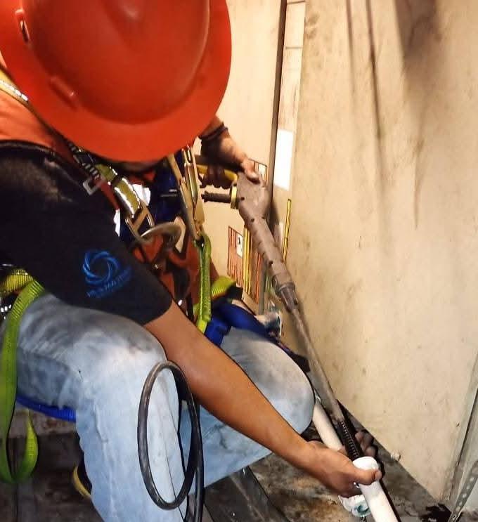 Trabajadores con cascos naranjas supervisando la instalación de un equipo industrial grande con grúa bajo cielo azul, con texto 'Ver Servicio Instalaciones'.