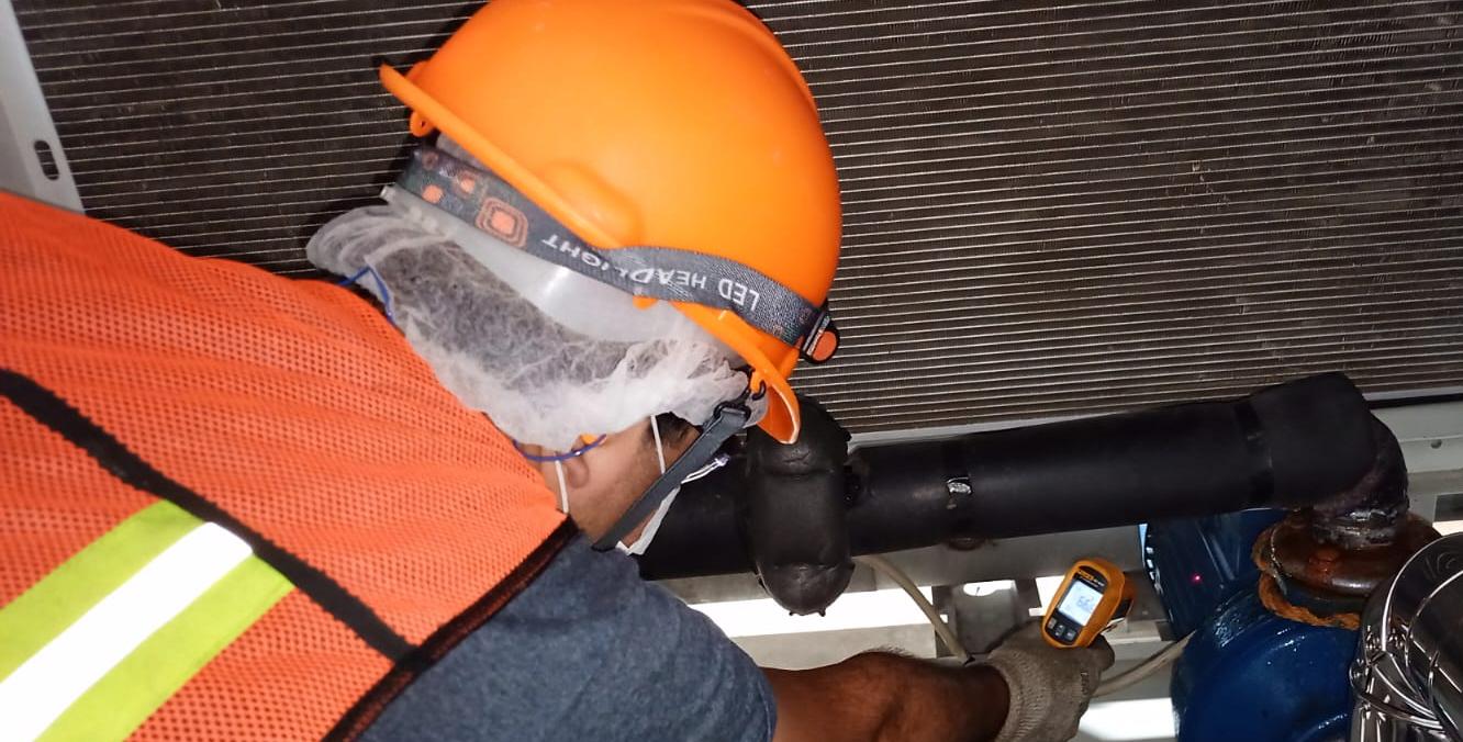 Trabajadores con cascos naranjas supervisando la instalación de un equipo industrial grande con grúa bajo cielo azul, con texto 'Ver Servicio Instalaciones'.