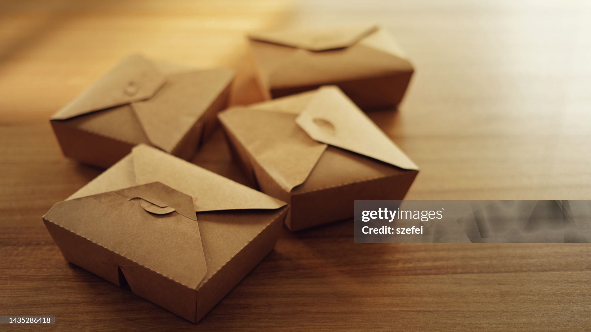 Cajas de cartón reciclado sobre una mesa de madera con fondo desenfocado.
