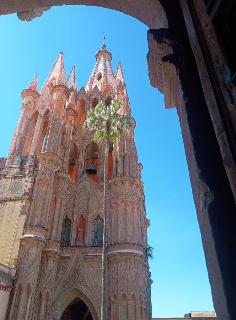 Plaza decorada con papel picado en colores mexicanos, con cielo despejado y palmeras.