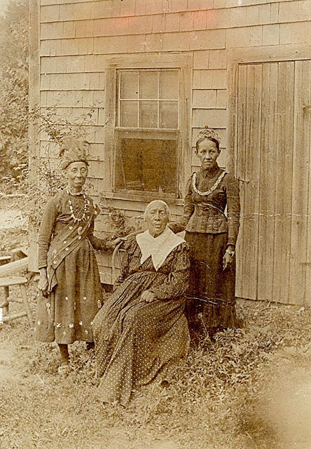Zerviah Gould Mitchell (seated) with her daughters Melinda (Teweelema) on left and Charlotte (Wootonekanuske) on right in front of their home at Betty's Neck in Lakeville, Massachusetts. Photo dated 1883