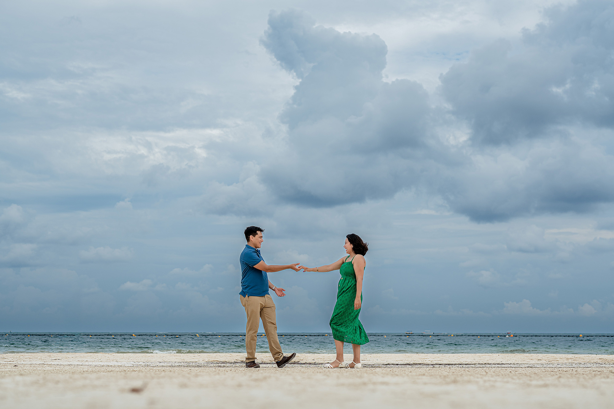 Novios caminando por la orilla del mar después de la pedida de mano, fotografía romántica en el Caribe Mexicano.