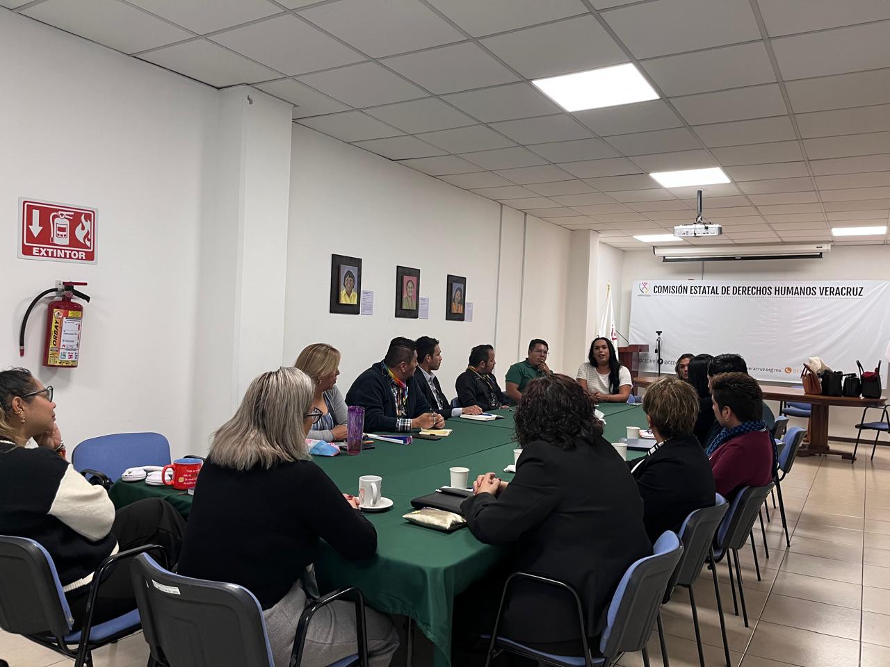 Reunión en la Comisión Estatal de Derechos Humanos Veracruz con personas sentadas alrededor de una mesa, discutiendo temas relacionados con derechos humanos.