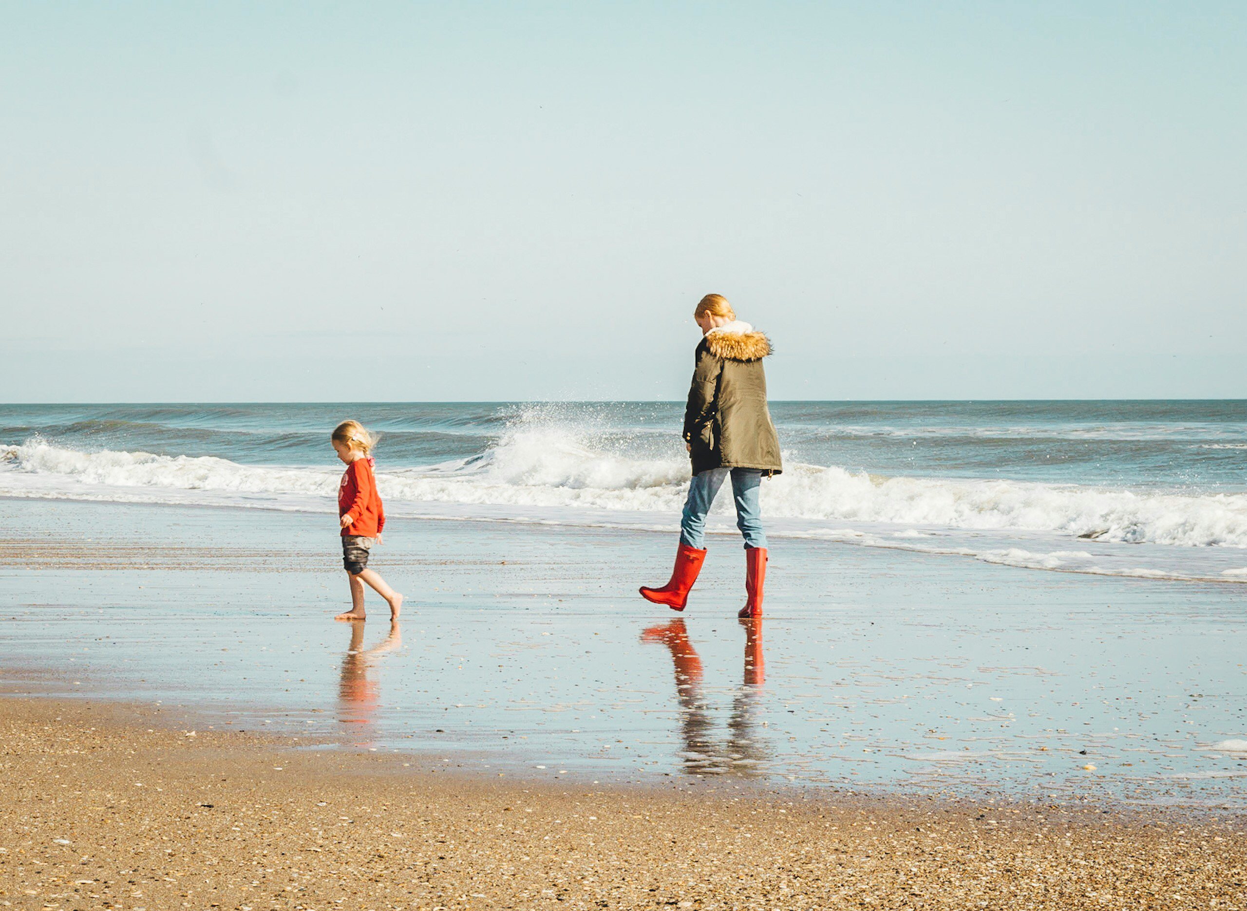 mujer y niño de pie en la orilla del mar